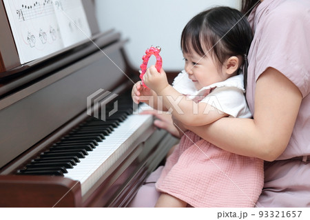 アップライトピアノを弾く1歳の女の子とママ 93321657