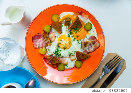 Fried eggs with bacon, croutons and pickles cucumber. Traditional Russian breakfast Fried eggs with bacon, croutons and pickles cucumber. Traditional Russian breakfast 93322605