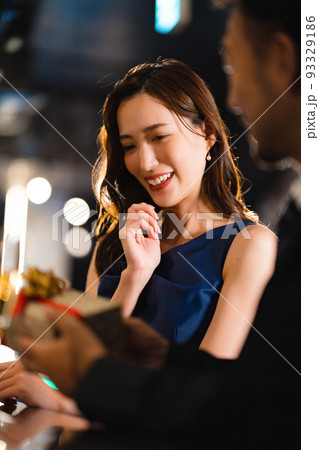 バーで美女にプレゼントを貢ぐ髭の男性 バーで美女にプレゼントを貢ぐ髭の男性 93329186