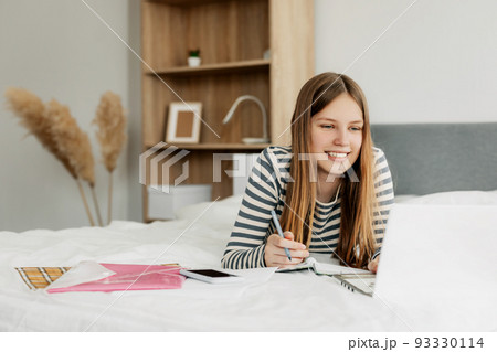 Portrait of a cute girl student preparing for lectures using a laptop. The concept of training and education, modern technologies Portrait of a cute girl student preparing for lectures using a laptop. The concept of training and education, modern technologies 93330114
