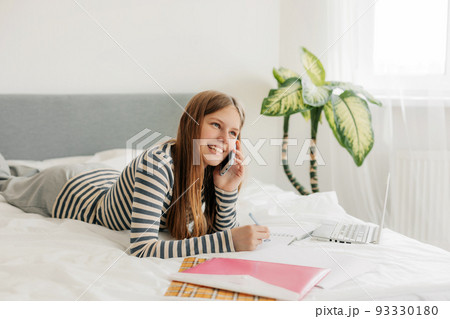 A student girl is talking on the phone, discussing homework with classmates. Modern technologies and communications in education A student girl is talking on the phone, discussing homework with classmates. Modern technologies and communications in education 93330180
