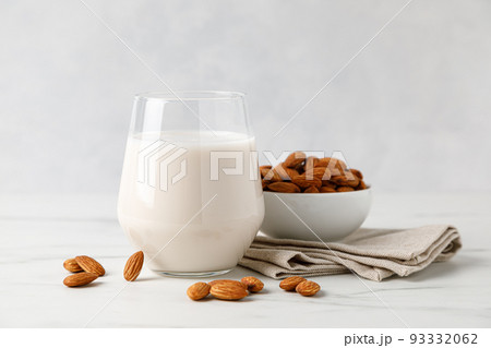 Almond milk in a glass and almond nuts Almond milk in a glass and almond nuts 93332062