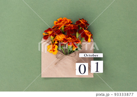 October 1. Bouquet of orange flower in craft envelope and calendar date on green background. Minimal concept Hello fall. Template for your design, greeting card October 1. Bouquet of orange flower in craft envelope and calendar date on green background. Minimal concept Hello fall. Template for your design, greeting card 93333877