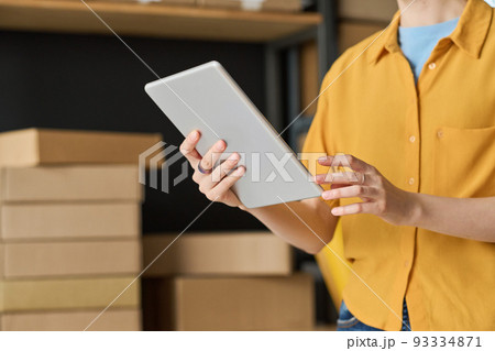 Close-up of woman using digital tablet to check track number while working in warehouse Close-up of woman using digital tablet to check track number while working in warehouse 93334871