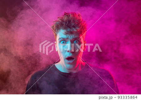 Shouting excited young man with bright emotions isolated over pink background with smoke. Concept of mental health, art, human emotions 93335864