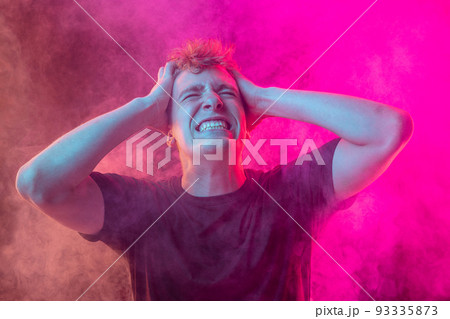 Emotional pain. Young man in deep emotional shock isolated over pink background with clouds of smoke. Concept of mental health, art, emotions Emotional pain. Young man in deep emotional shock isolated over pink background with clouds of smoke. Concept of mental health, art, emotions 93335873