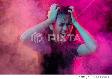 Emotional pain. Young dark hair woman shouting isolated over neoned pink background with clouds of smoke. Concept of mental health, art, emotions Emotional pain. Young dark hair woman shouting isolated over neoned pink background with clouds of smoke. Concept of mental health, art, emotions 93335904