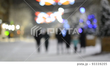 Blurred background. City street during snowfall at winter night. Beautiful illumination and decoration on street. New Year Christmas holidays celebration. Lanterns garlands on trees. 93339205