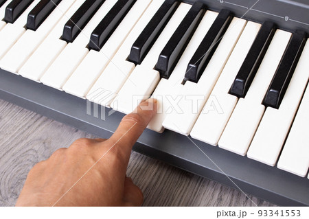 Finger presses the white piano key closeup Finger presses the white piano key closeup 93341553