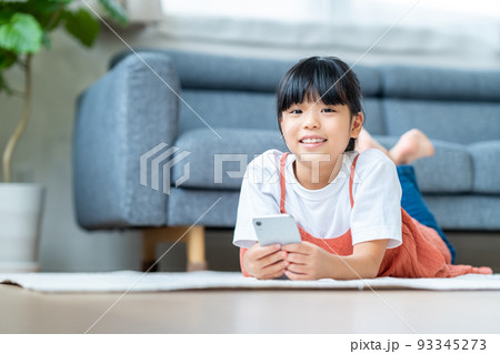 リビングでスマホをする小学生の女の子 93345273