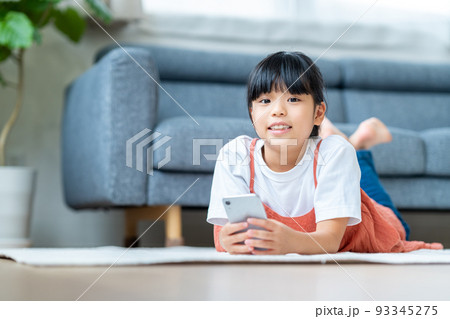 リビングでスマホをする小学生の女の子 リビングでスマホをする小学生の女の子 93345275