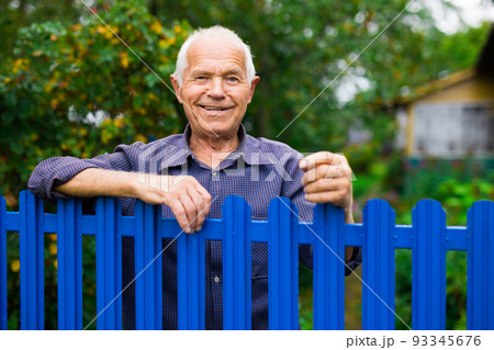 Portrait of pensive elderly man at fence of his country house in village Portrait of pensive elderly man at fence of his country house in village 93345676