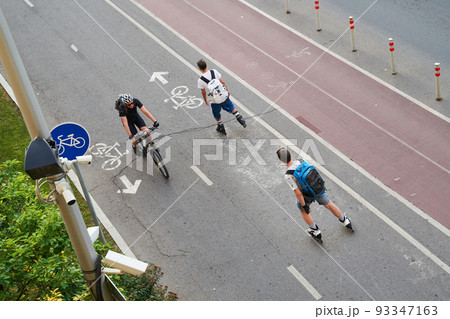 Top aerial view of cyclist and two inline skaters on cycling road. Top aerial view of cyclist and two inline skaters on cycling road. 93347163