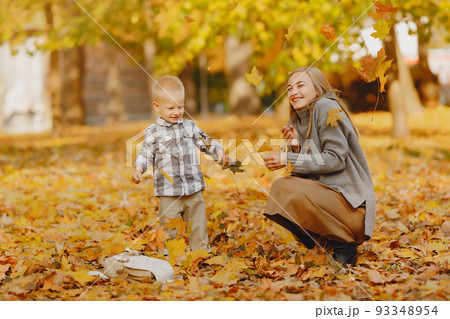 Family in a autumn park. Mother in a brown sweater. Cute little boy in a shirt Family in a autumn park. Mother in a brown sweater. Cute little boy in a shirt 93348954