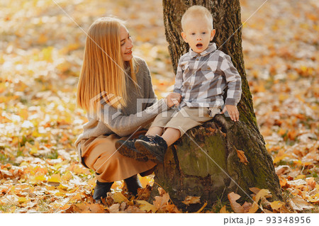 Family in a autumn park. Mother in a brown sweater. Cute little boy in a shirt Family in a autumn park. Mother in a brown sweater. Cute little boy in a shirt 93348956