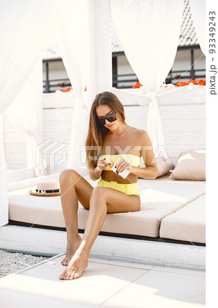 Woman applying sunscreen lotion on her legs, while lying on the sunbed. 93349243