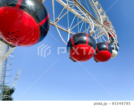 amusement park. Ferris wheel made of white metal. On the wheel there are large cabins for riding red tourists amusement park. Ferris wheel made of white metal. On the wheel there are large cabins for riding red tourists 93349795