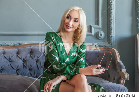 Beautiful blonde woman in fashionable green dress indoor portrait Beautiful blonde woman in fashionable green dress indoor portrait 93350842