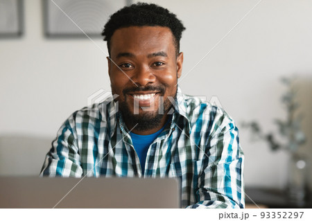 Cheerful African American Male Using Laptop Smiling To Camera Indoor 93352297