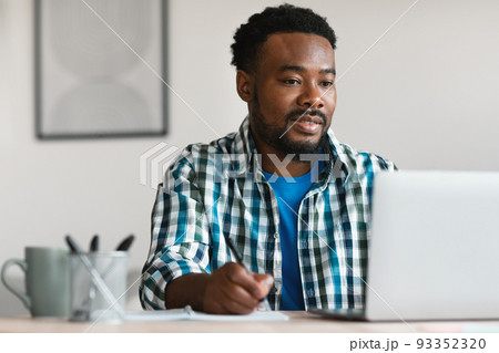 Black Man Freelancer Using Laptop Working Taking Notes At Workplace Black Man Freelancer Using Laptop Working Taking Notes At Workplace 93352320