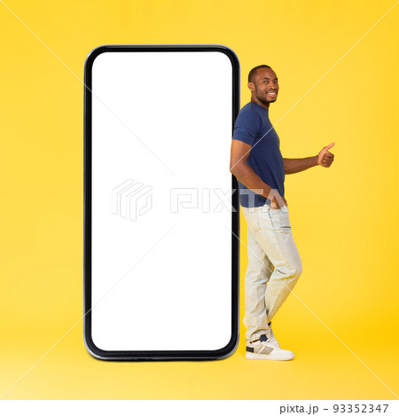 African Guy Leaning On Smartphone Gesturing Thumbs Up, Yellow Background 93352347