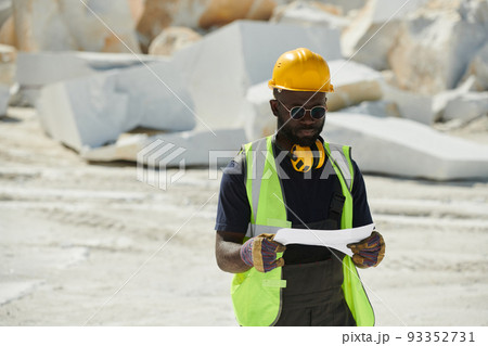 Young African American engineer in gloves, hardhat, uniform and eyeglassess 93352731