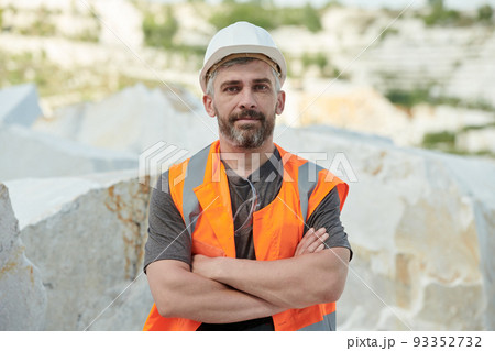 Confident mature foreman in hardhat and workwear crossing arms on chest 93352732