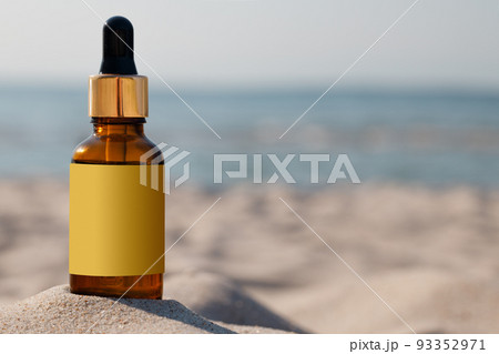 Mock-up for a medicinal or cosmetic product. A bottle with a dropper and gold cap on the sand of the beach, copy space. Mock-up for a medicinal or cosmetic product. A bottle with a dropper and gold cap on the sand of the beach, copy space. 93352971