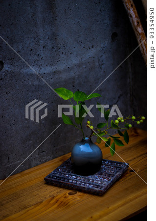 玄関先でモルタルをバックに黒とブルーのガラス製の花瓶に活けた樹々の緑 玄関先でモルタルをバックに黒とブルーのガラス製の花瓶に活けた樹々の緑 93354950