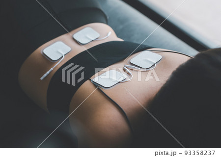 Physical therapy for woman patient with TENS electrode pads on back,Preparing equipment 93358237