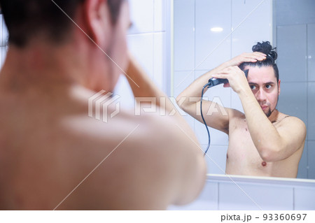 鏡に映る髪の毛をセルフカットする男性 93360697