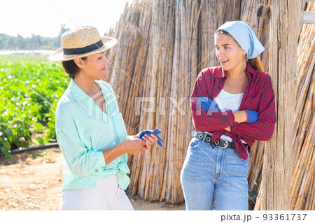 Two female farmers communicate during a working break 93361737