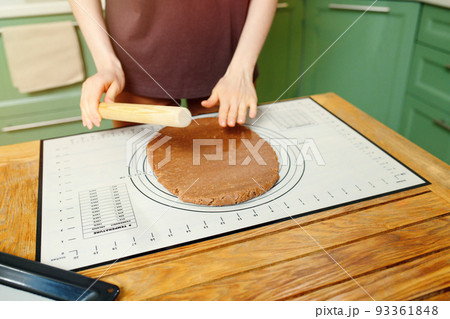 Rolling out shortcrust pastry for home bakery on a silicone baking mat on a wooden table Rolling out shortcrust pastry for home bakery on a silicone baking mat on a wooden table 93361848