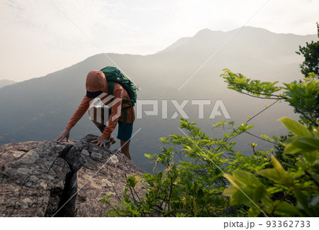 Suceesful woman hiker climbing up at the cliff edge on mountain top Suceesful woman hiker climbing up at the cliff edge on mountain top 93362733