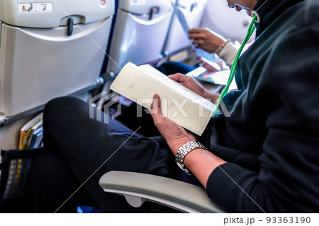 attendence passenger read book on the plane seat. 93363190