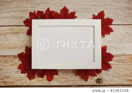 Empty mock up photo frame with maple leaves on wooden background 93365206