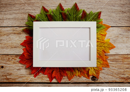Empty mock up photo frame with maple leaves on wooden background 93365208