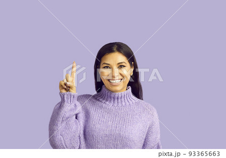 Pretty young female with pleasant smile, makes gesture with index finger, points upwards Pretty young female with pleasant smile, makes gesture with index finger, points upwards 93365663