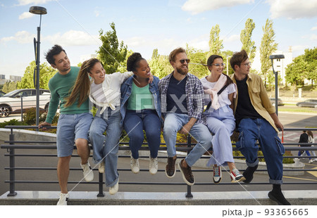 Group of stylish, cheerful and friendly multiracial men and women walking together in city center. Group of stylish, cheerful and friendly multiracial men and women walking together in city center. 93365665