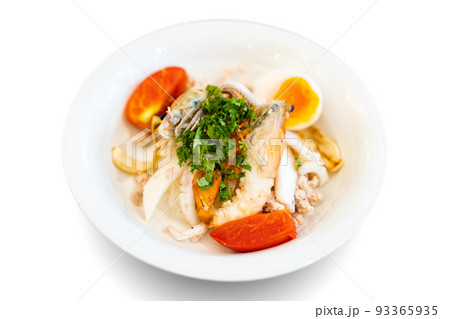 Seafood Thai noodle mixxed together between boiled shrimp, squid, pork, egg and colourful vegetable in white bowl. 93365935