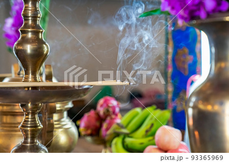 Incense on the brass candlestrick with the smoke out from incense. 93365969