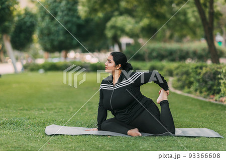 An Indian girl practices yoga in a summer park in the afternoon, resting after a hard day. Practice, yoga, fitness 93366608