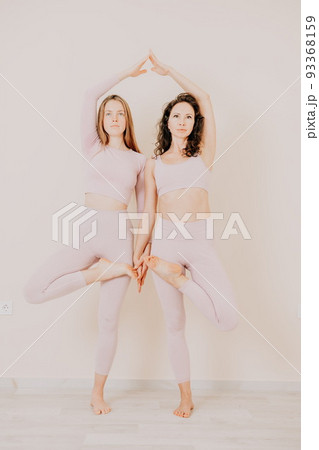 Well looking middle aged sporty woman, fitness instructor in pink sportswear doing stretching and pilates on yoga mat in the studio with mirror. Female fitness yoga. Healthy lifestyle and harmony. 93368159
