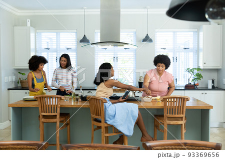 Biracial female friends preparing pizza on kitchen island while spending weekend together at home Biracial female friends preparing pizza on kitchen island while spending weekend together at home 93369656