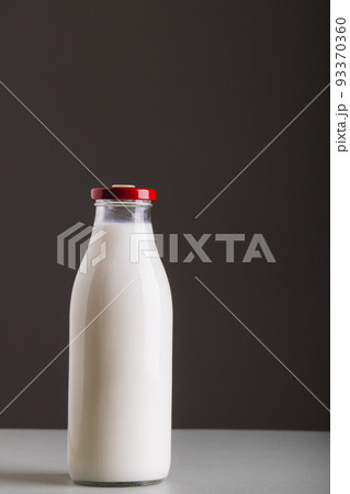 Milk in glass bottle on table against gray background with copy space Milk in glass bottle on table against gray background with copy space 93370360