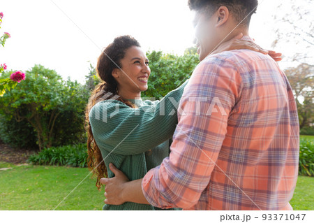 Happy biracial couple embracing and smiling on terrace in garden Happy biracial couple embracing and smiling on terrace in garden 93371047