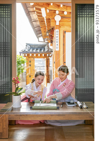Korean and Caucasian girls Experiencing traditional calligraphy in Hanok, Korean traditional house Korean and Caucasian girls Experiencing traditional calligraphy in Hanok, Korean traditional house 93373579