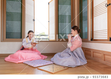 Korean and Caucasian girls wearing Hanbok playing Yut, Korean traditional board game 93373683
