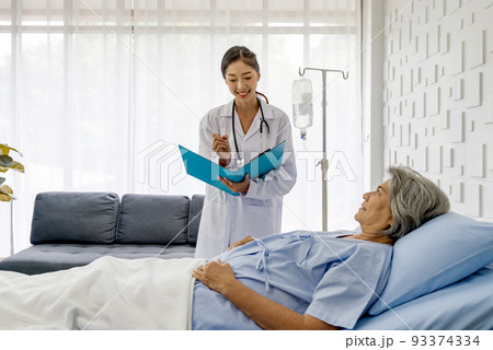 Young asian doctor in white gown with stethoscope and document folder, examine the symptom of the elderly patient in the recovery room. Healthcare and medicine concept Young asian doctor in white gown with stethoscope and document folder, examine the symptom of the elderly patient in the recovery room. Healthcare and medicine concept 93374334