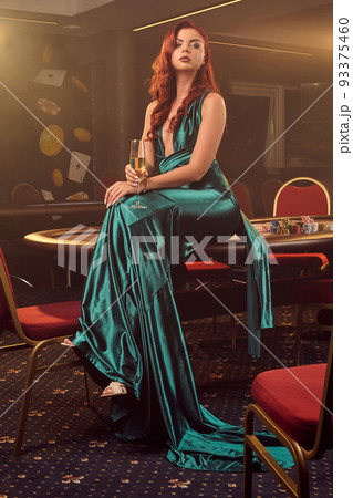 Young beautiful woman is posing against a poker table in luxury casino. Young beautiful woman is posing against a poker table in luxury casino. 93375460